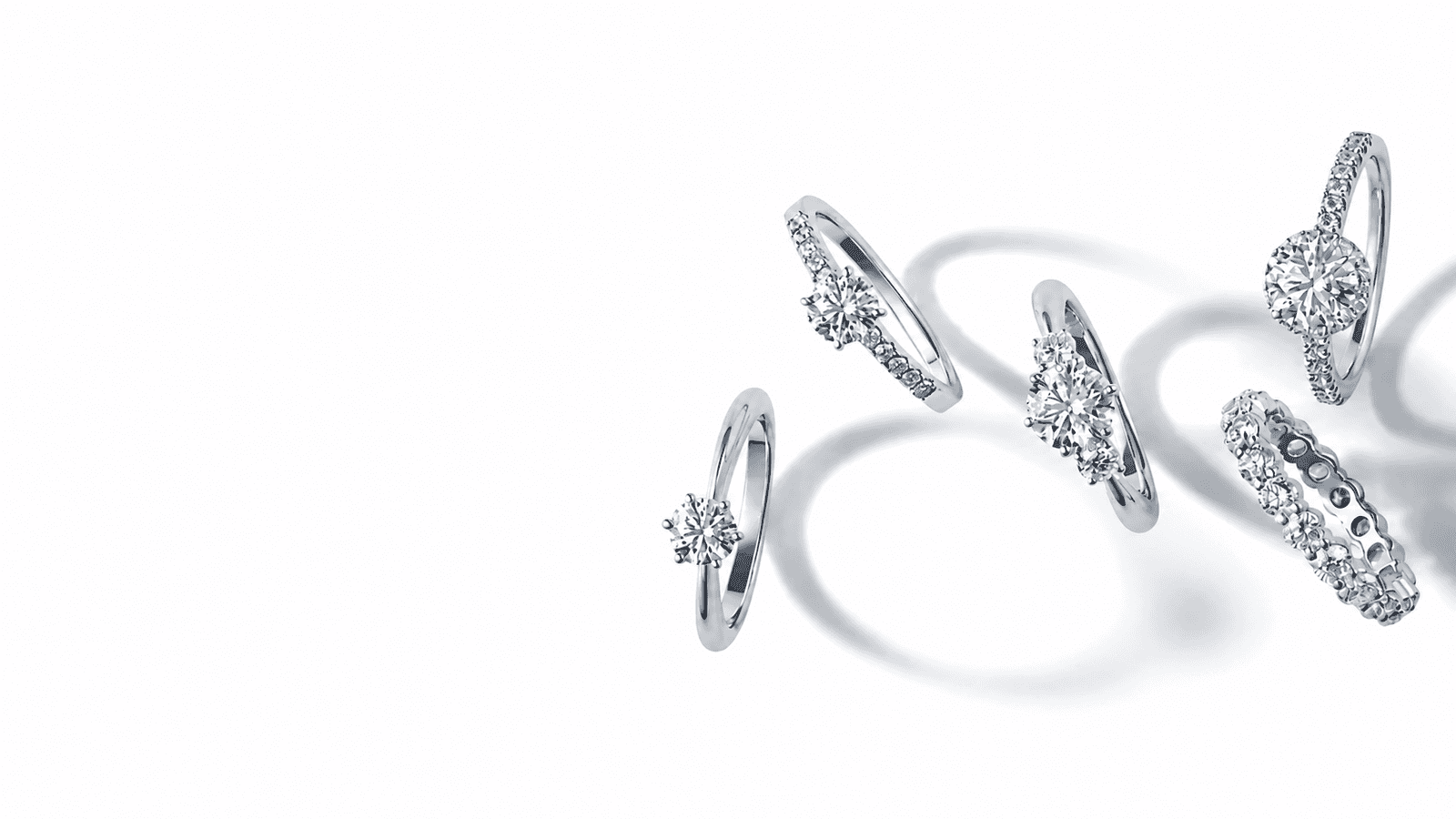 Collection of diamond engagement rings arranged on a soft white surface