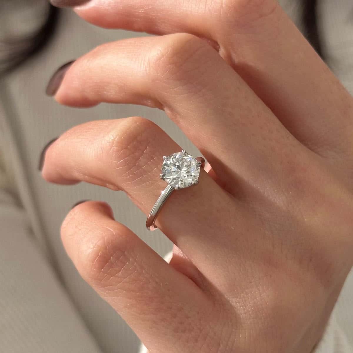 Hand wearing a solitaire diamond engagement ring